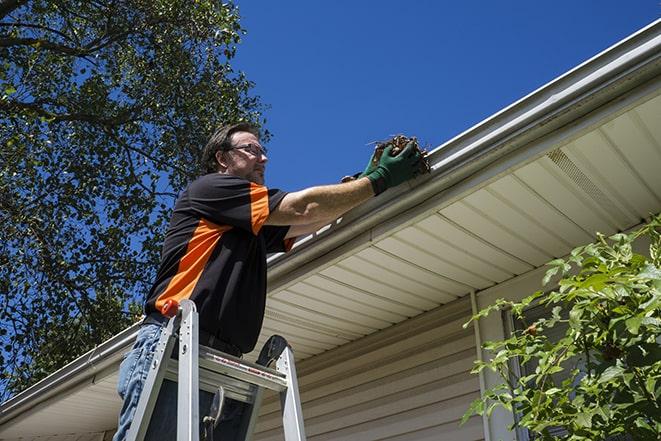 a person repairing a gutter on a residential roof in Blauvelt